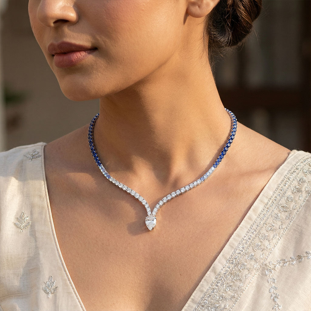 Elegant blue sapphire and diamond necklace for women with modern V-shaped design, styled with a light ethnic outfit