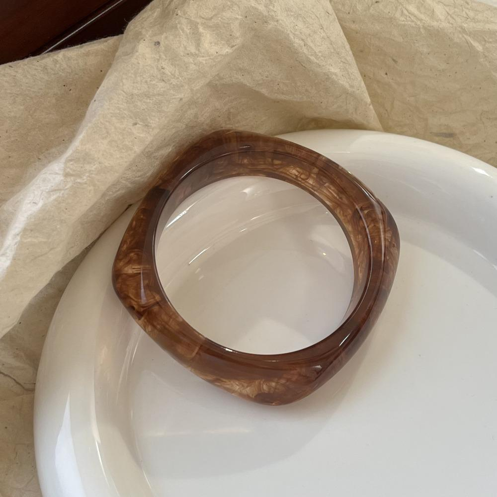 Brown bangle on a white plate with a beige cloth background