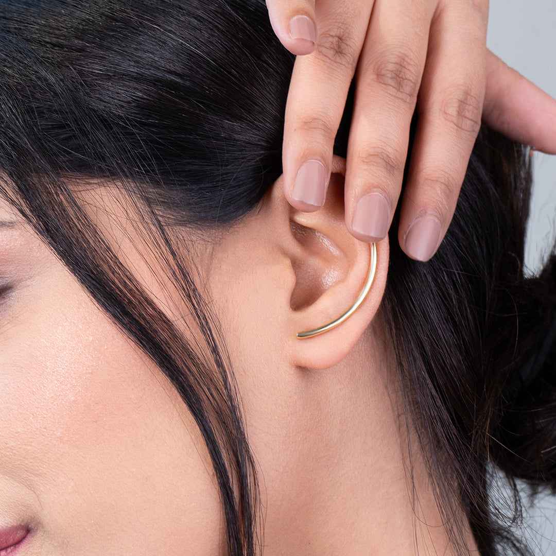 Close-up of a person wearing a gold Designer earrings for women with a neutral background