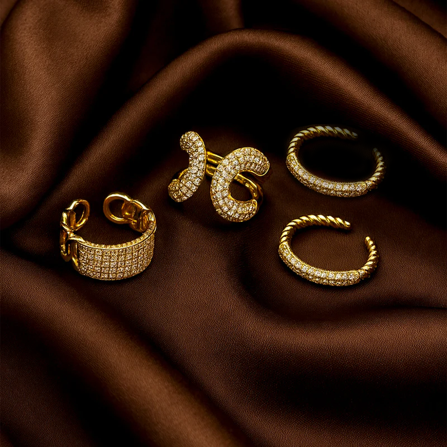 Gold designer rings on a brown fabric background
