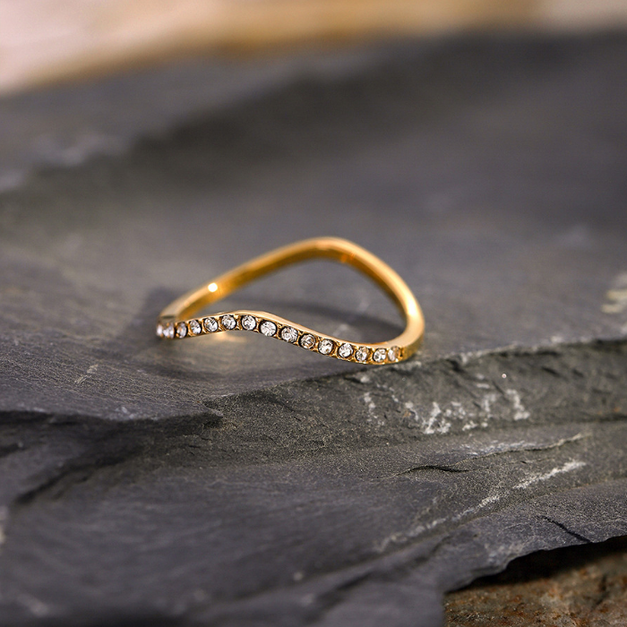 Gold ring with small diamonds on a dark stone surface