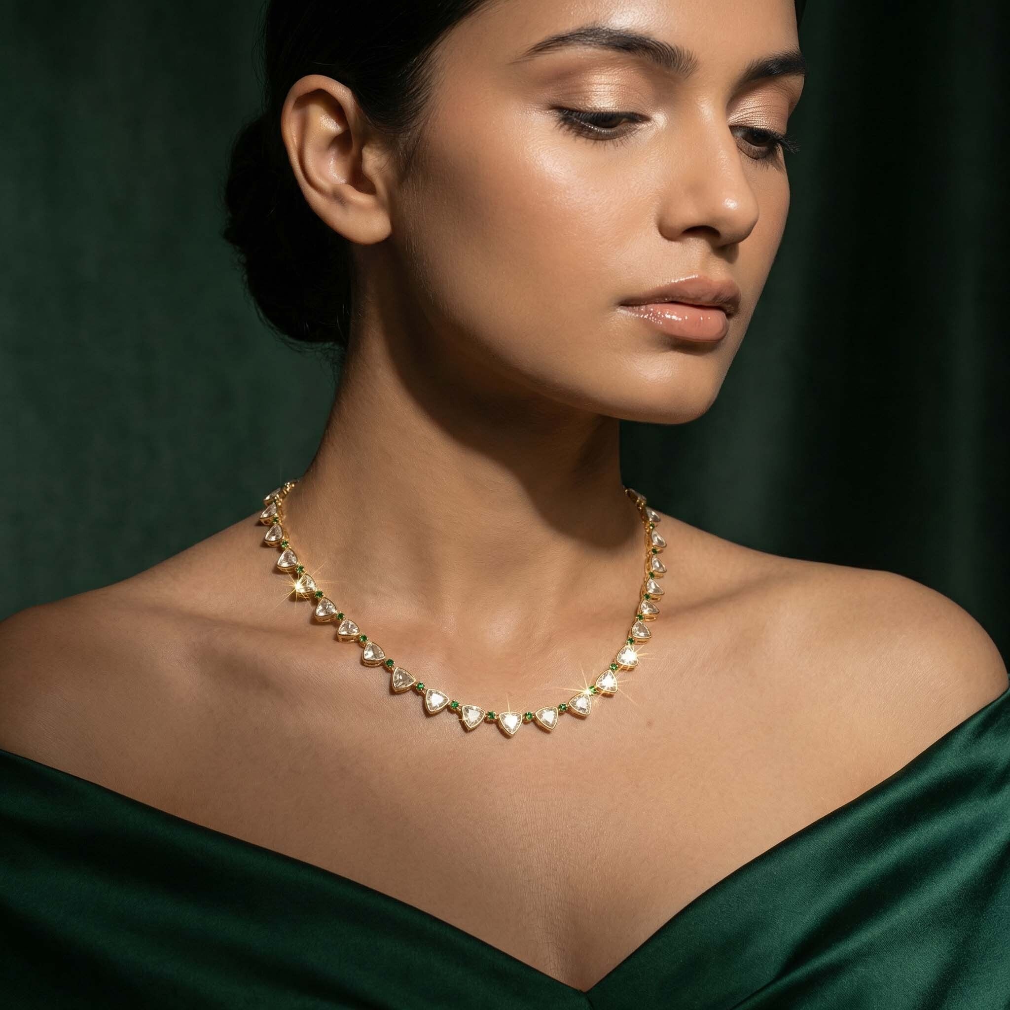 Woman wearing a gold and green necklace against a dark green background