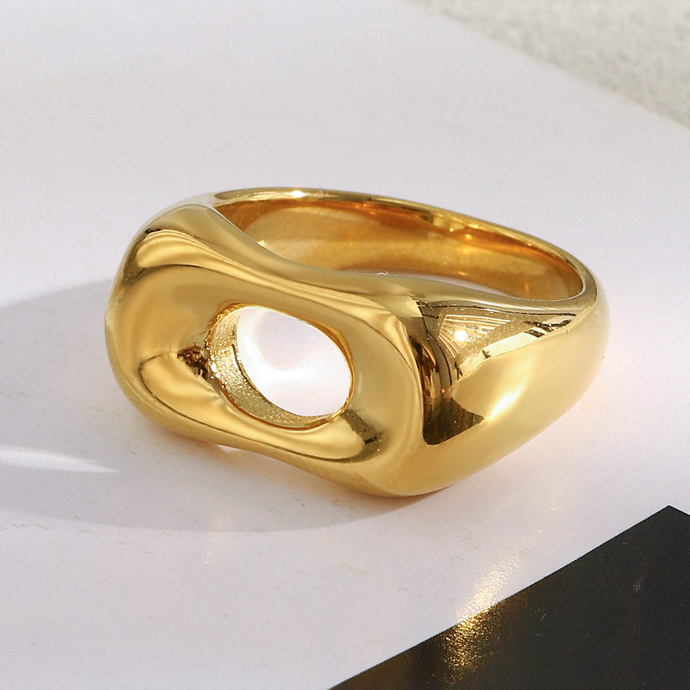 Gold ring with a central stone on a white surface
