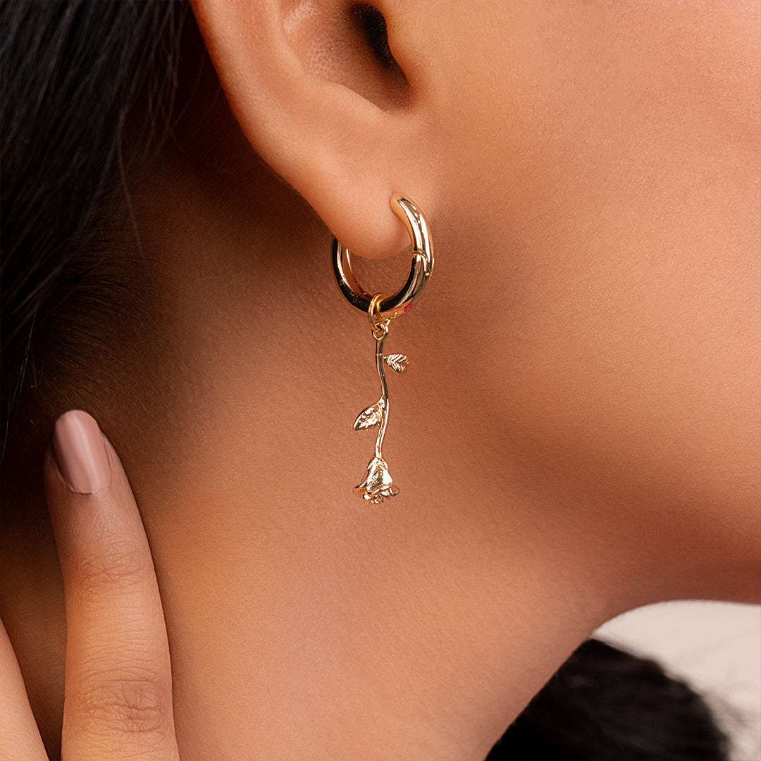 Gold hoop earrings for women with floral design worn by a person