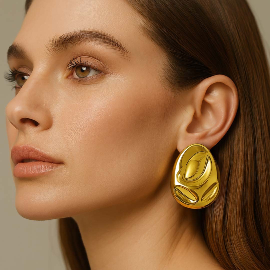 Close-up of a woman wearing a gold earrings for women against a neutral background