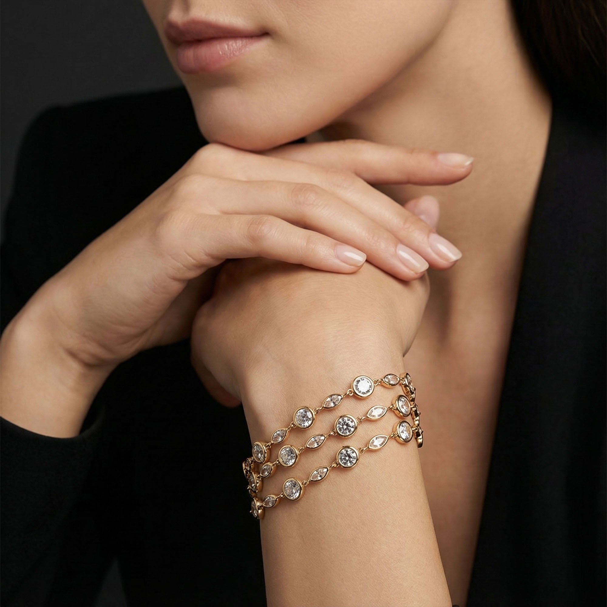Close-up of a woman's arm wearing a rose gold bracelet with clear stones against a dark background