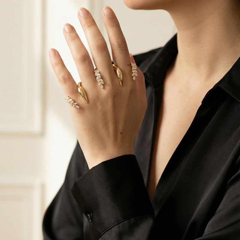Close-up of a person wearing gold rings with pearl accents on a blurred background