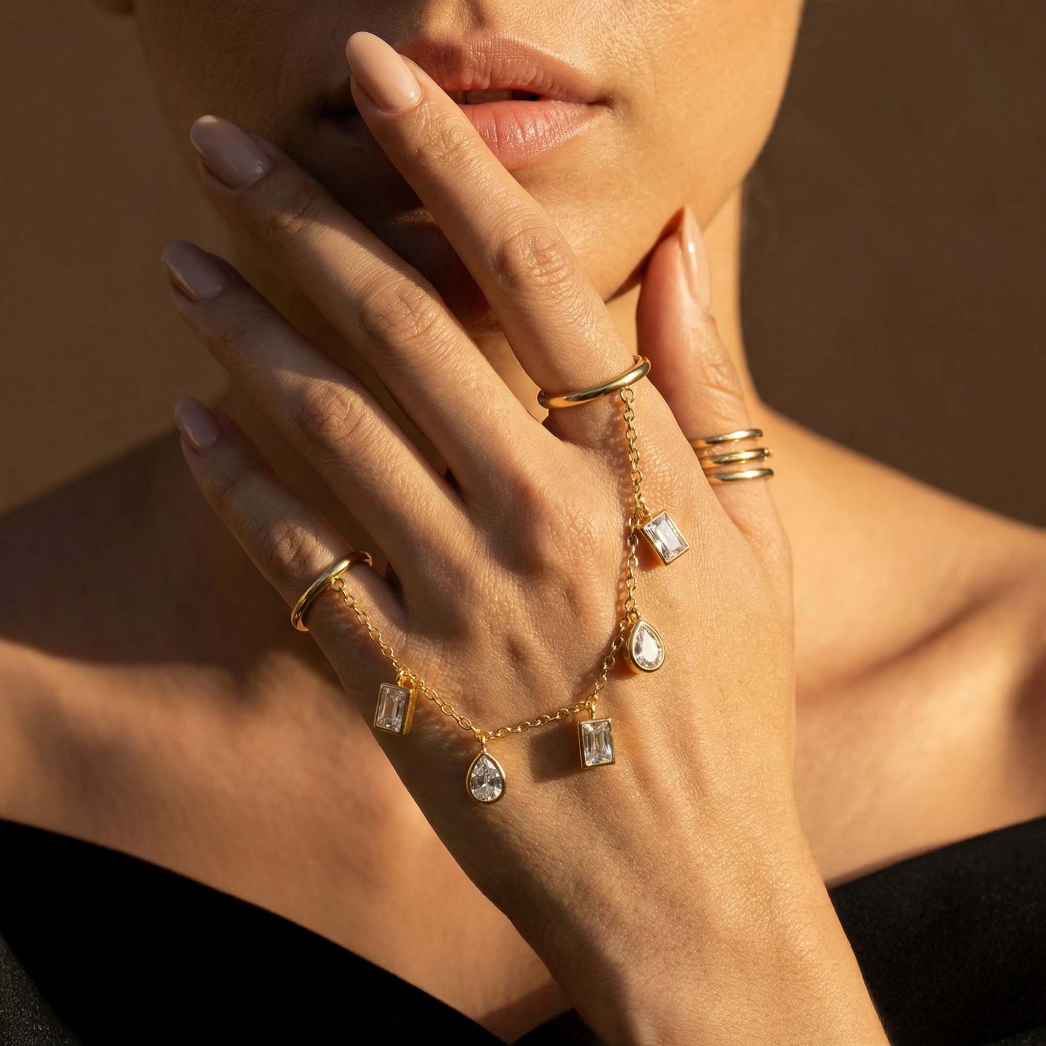 Close-up of a hand wearing gold jewelry with a blurred background