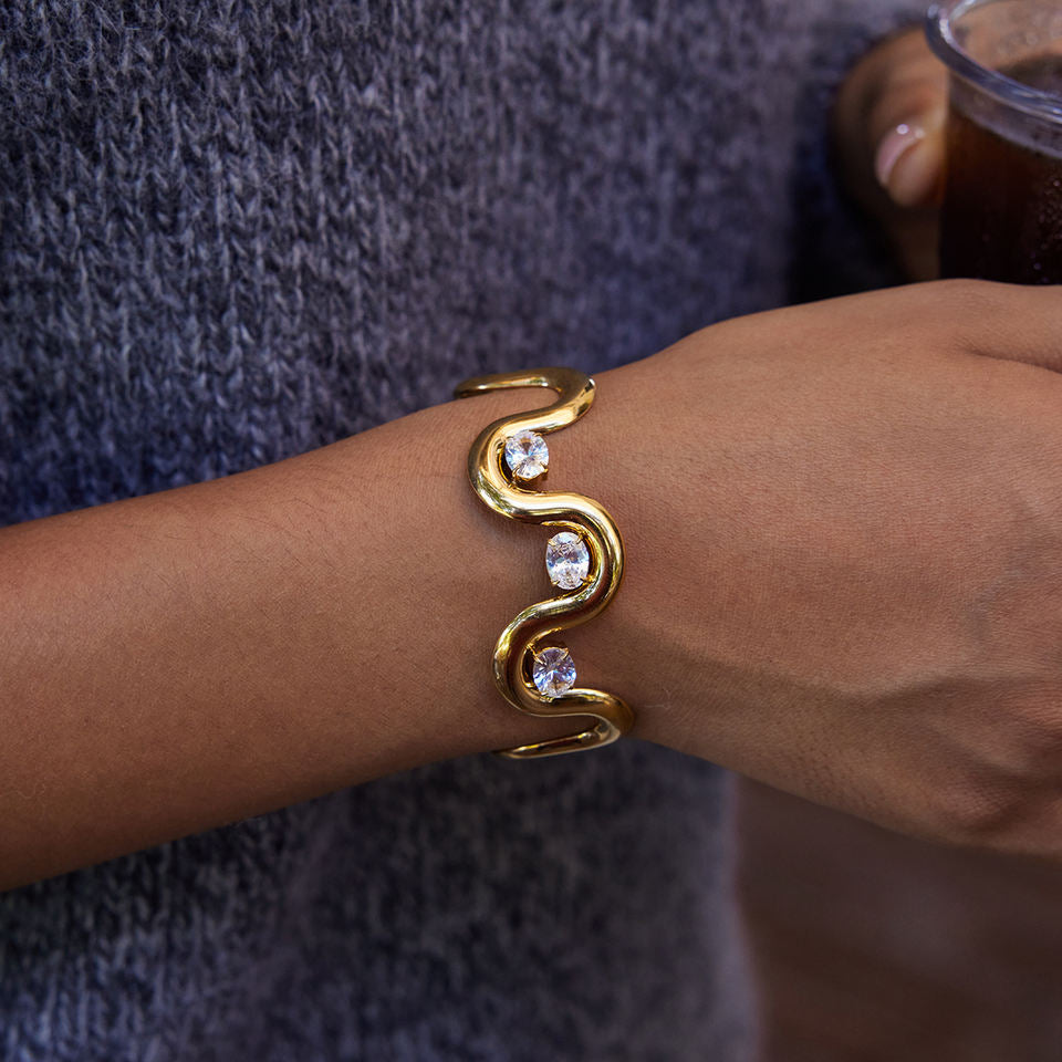 Gold wave cuff bracelet for women with round crystal stones worn on wrist