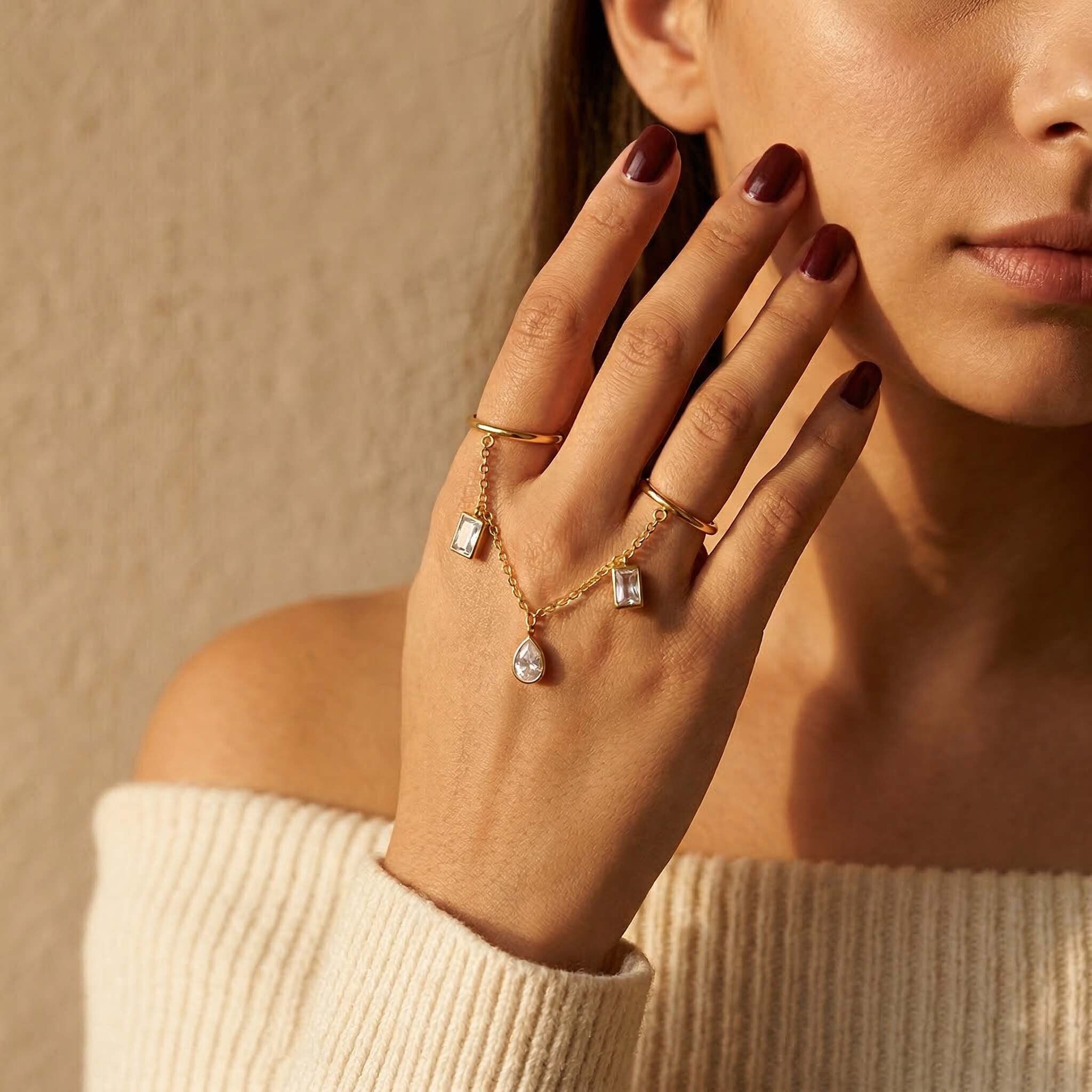 Woman wearing a gold double-finger ring with delicate chain links and crystal charms, styled as elegant party wear and occasion jewellery