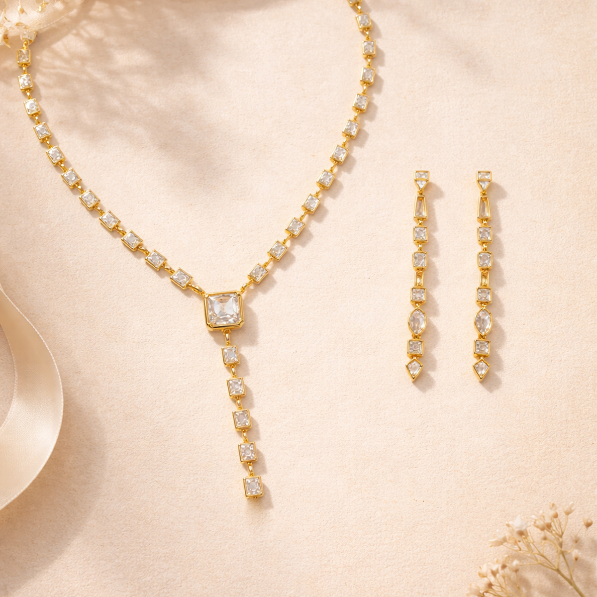 Gold necklace and earrings set on a beige background