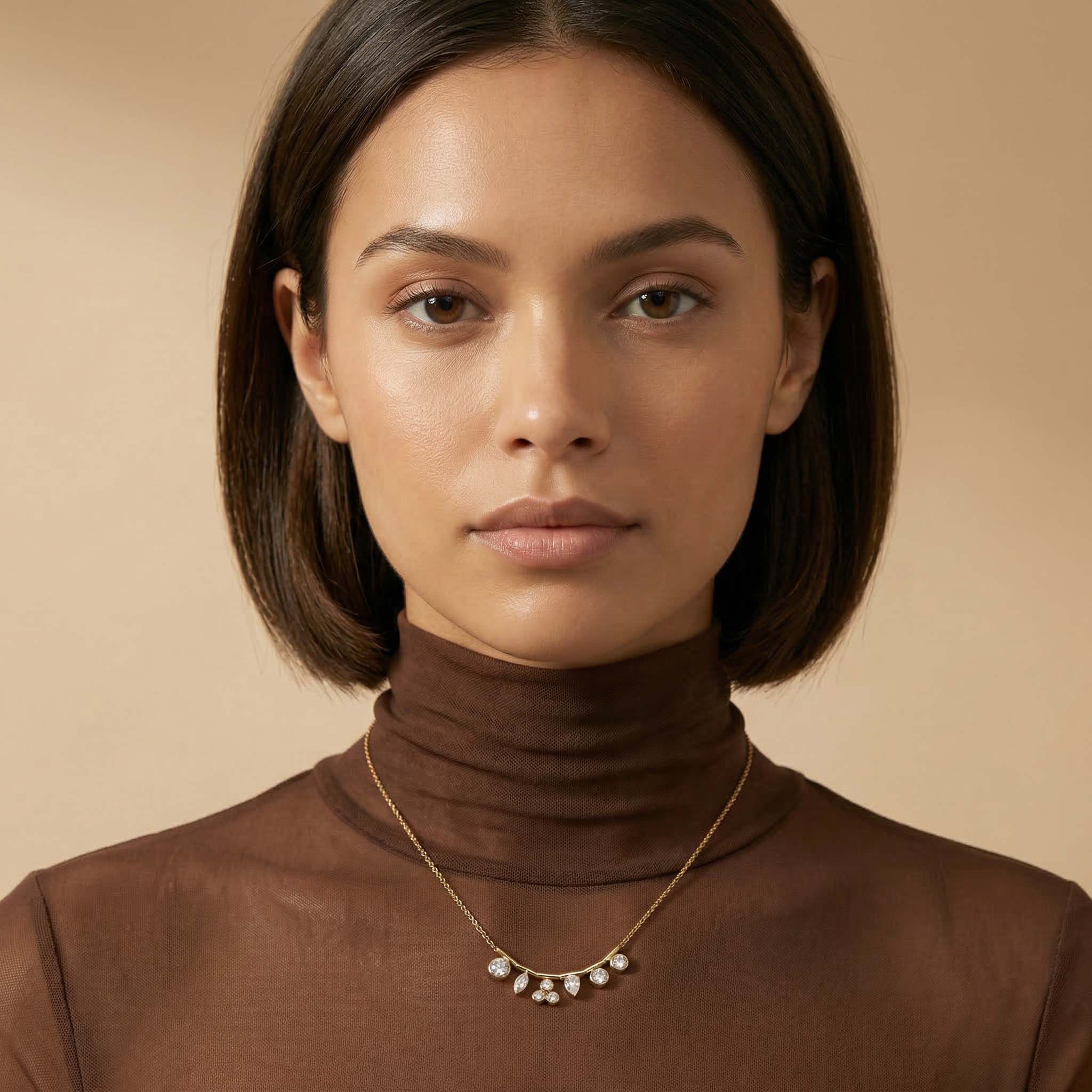 Woman wearing a brown turtleneck and necklace against a beige background