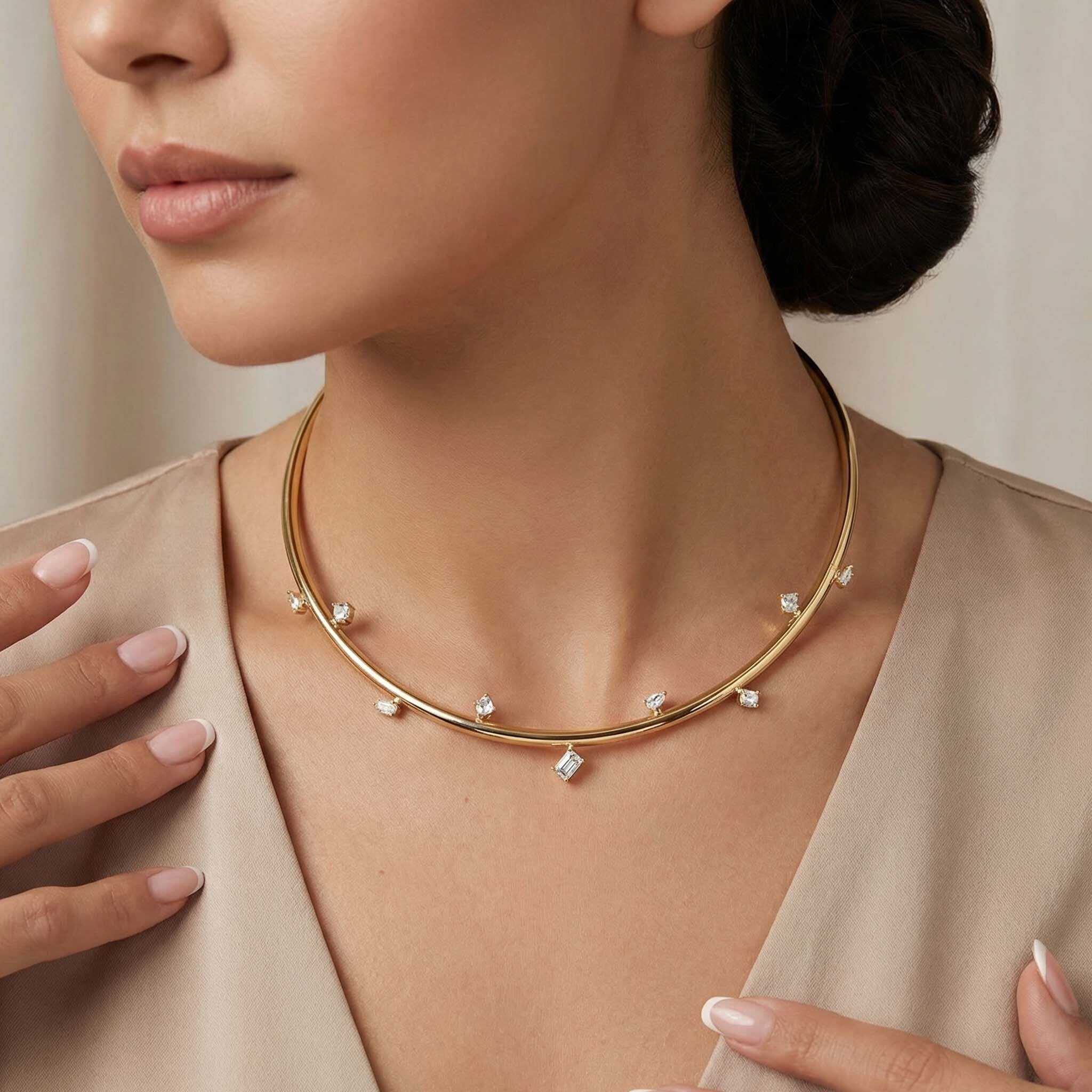 Gold necklace with small diamonds worn by a model against a neutral background