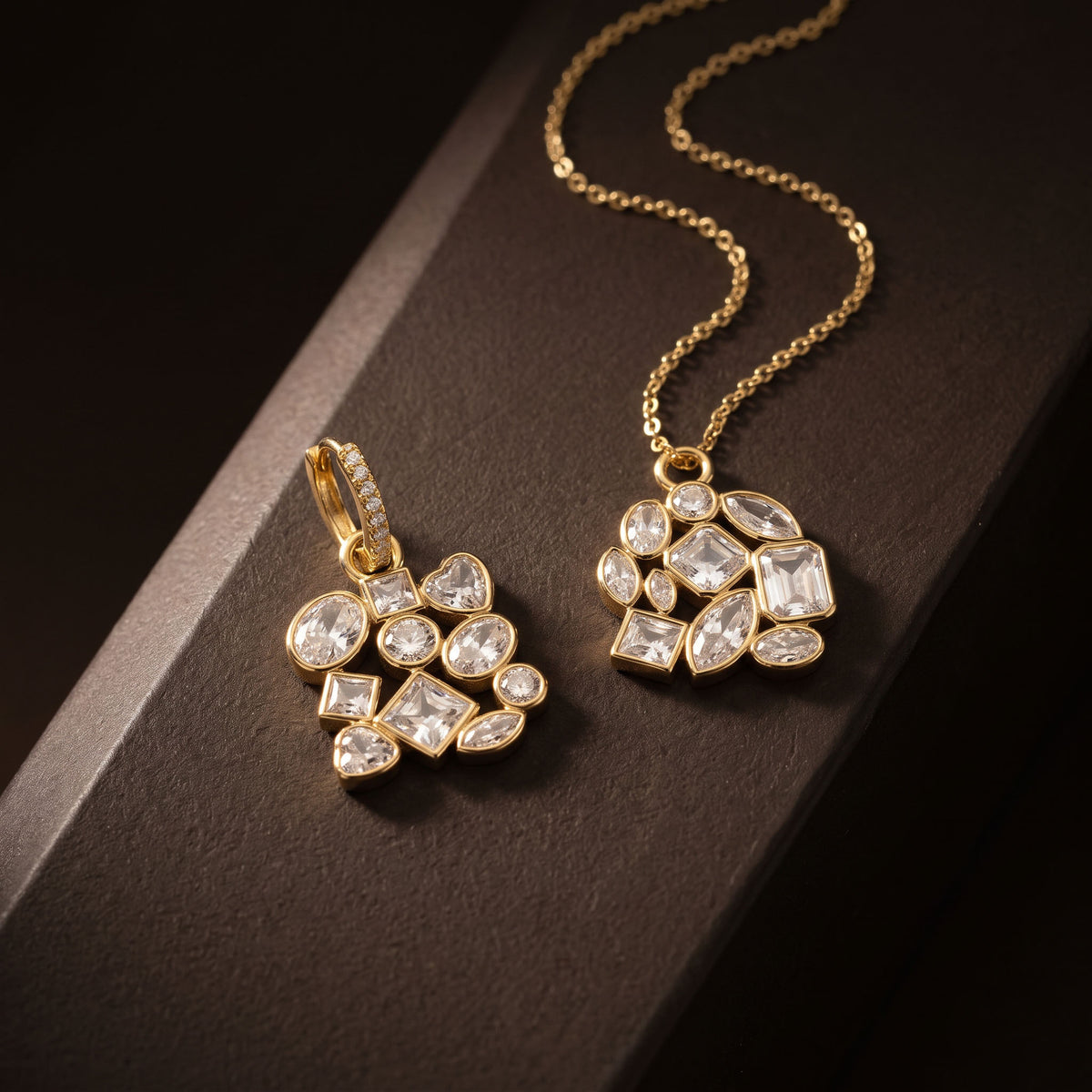 Gold pendant necklace and matching earrings with clear faceted gemstones arranged on a dark brown surface.
