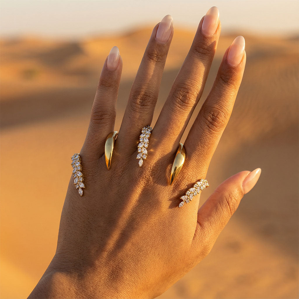Hand wearing Gold Knuckle Ring with a desert landscape in the background
