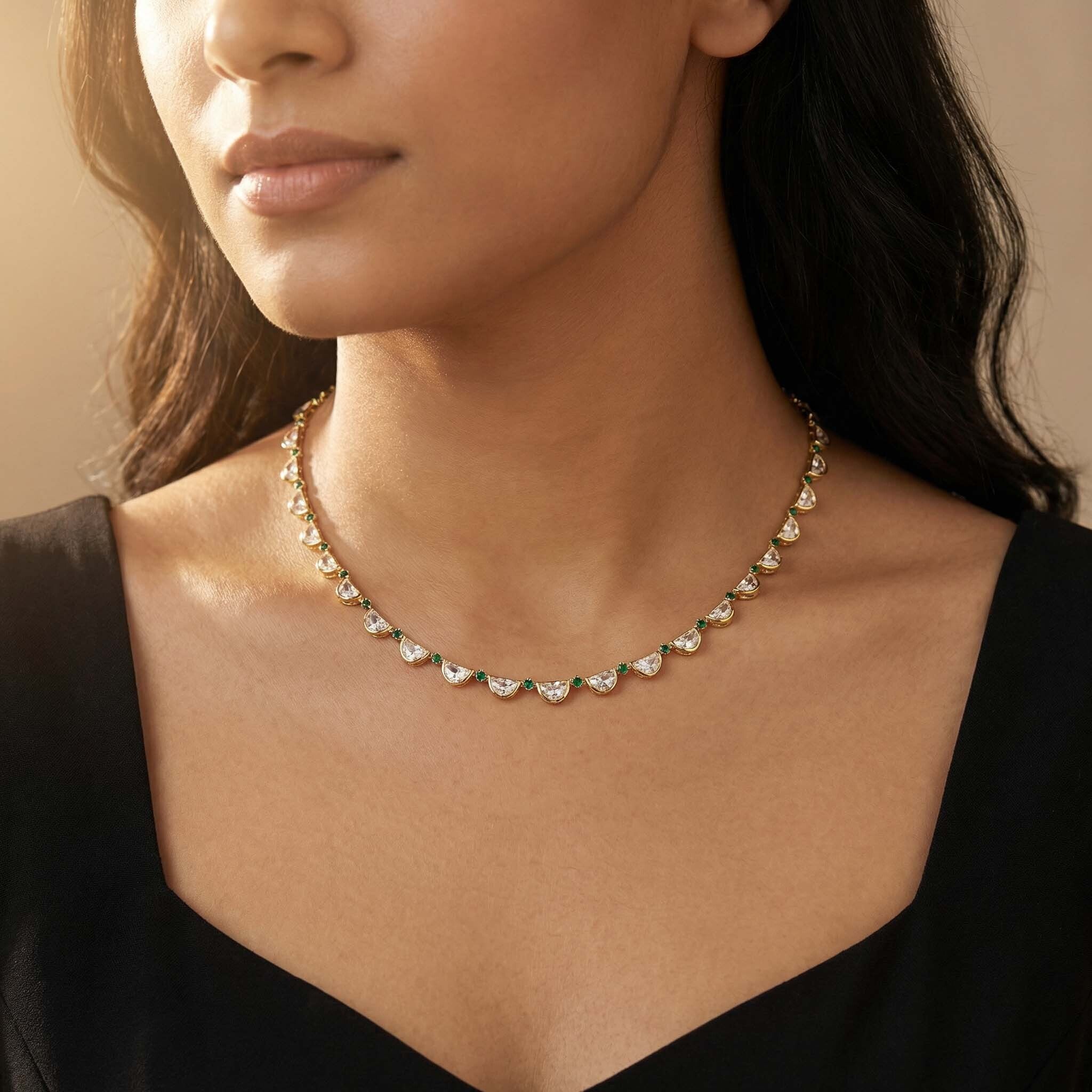 Gold necklace with white stones and green details worn by woman
