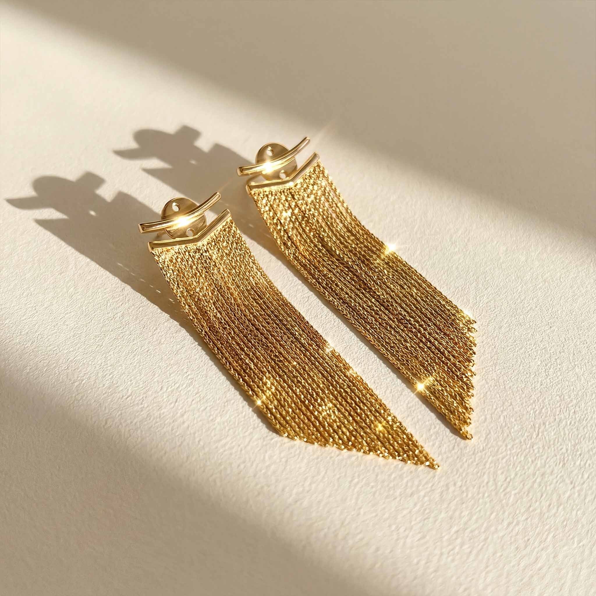 Gold fringe earrings for women on a light beige background