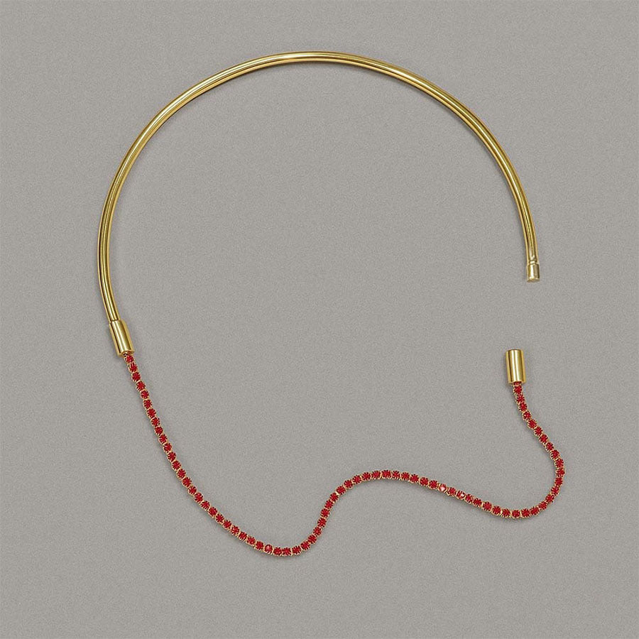 Gold necklace with red beads on a gray background
