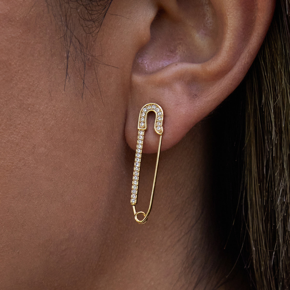 Gold safety pin earrings for women worn on an ear