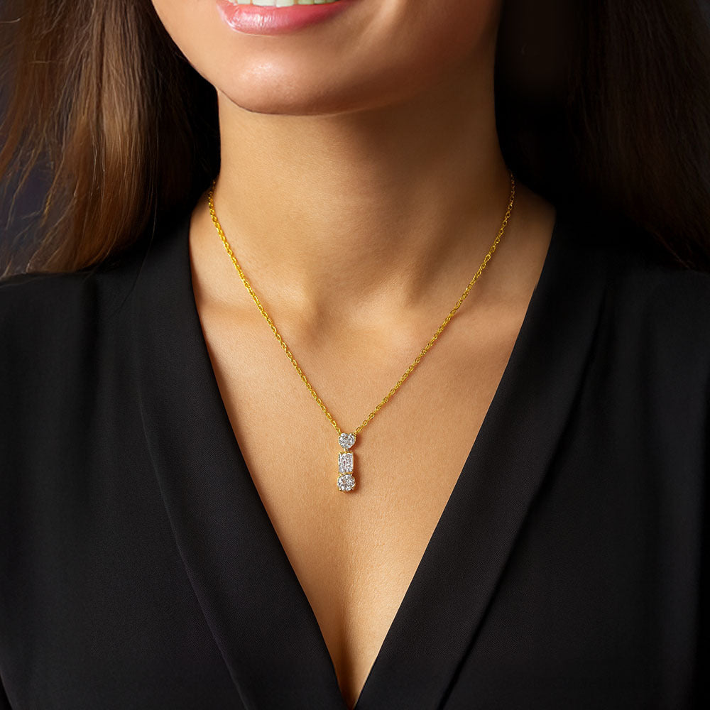 Gold necklace with a diamond pendant worn by a person in a black outfit.