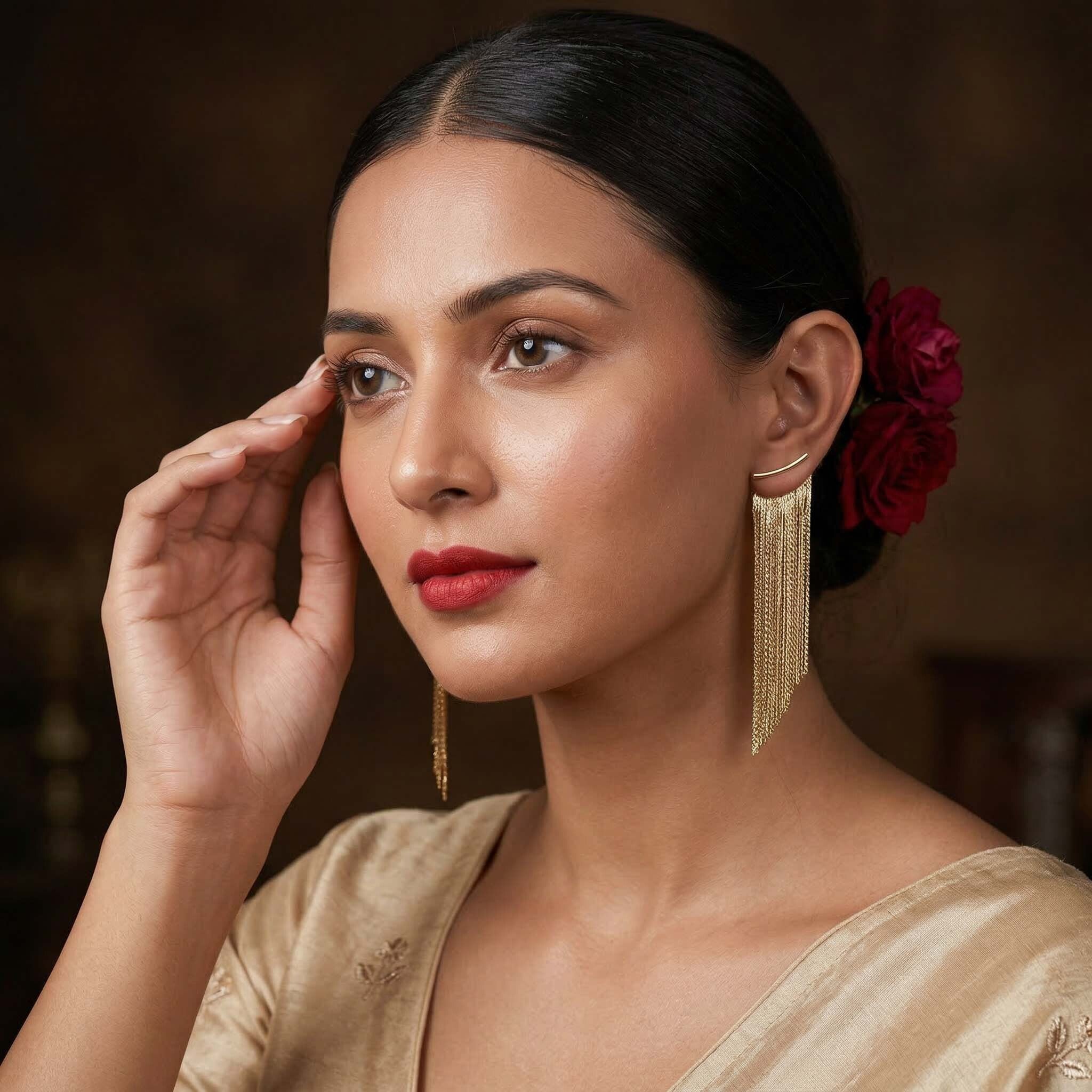 Woman wearing gold earrings for women with a red flower in her hair against a dark background