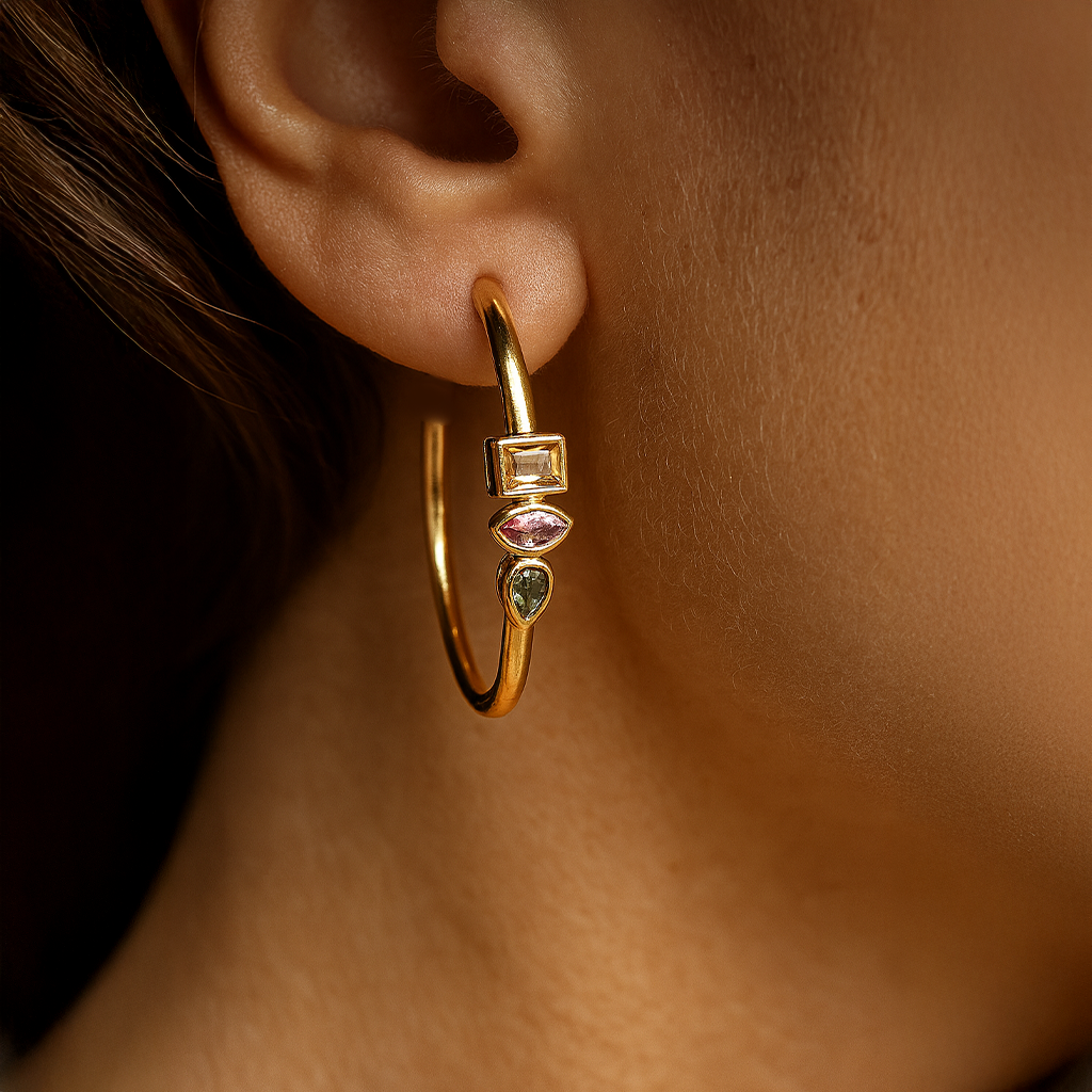 Gold hoop earring with gemstones worn by a person
