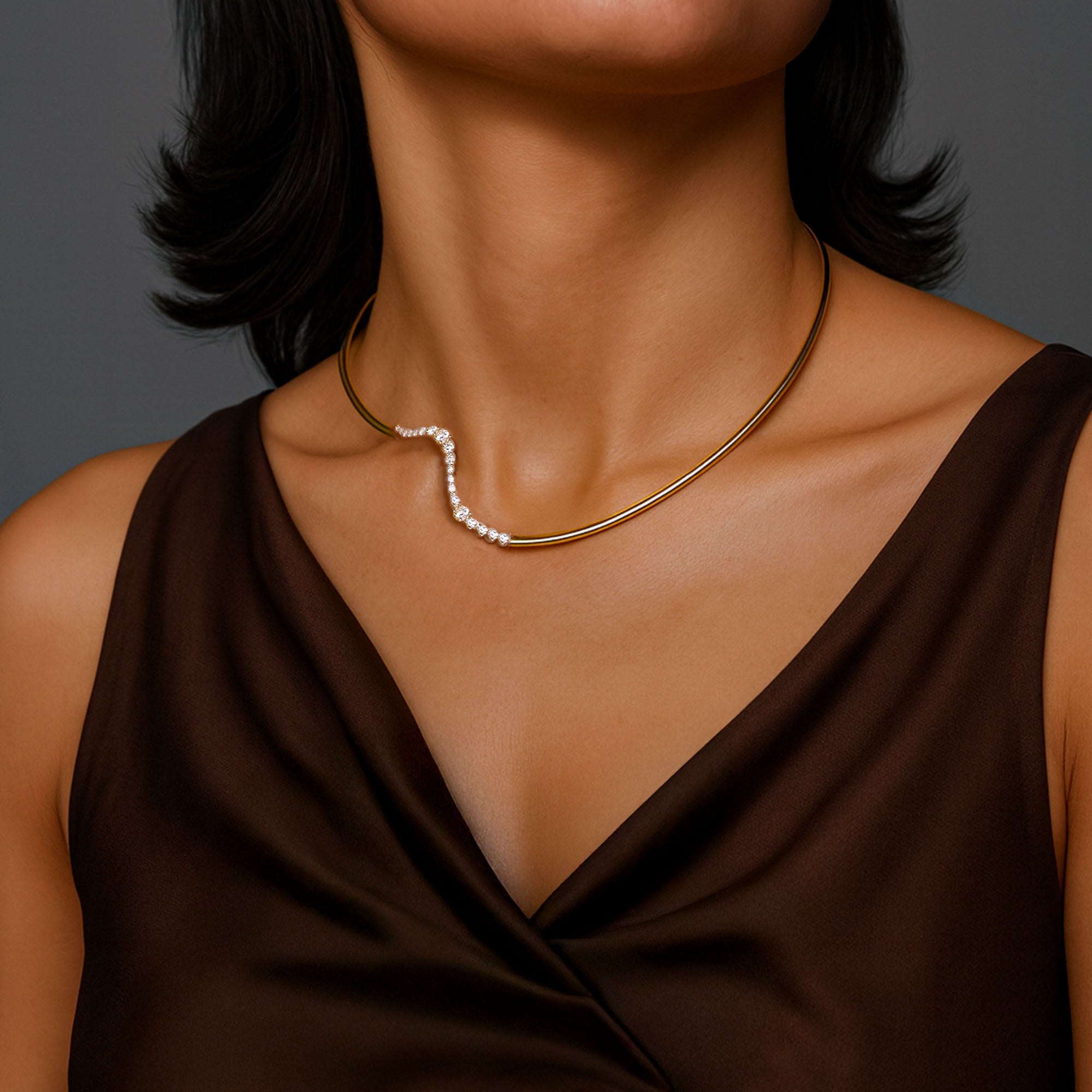 Necklace diamond choker worn by a person in a brown top against a gray background