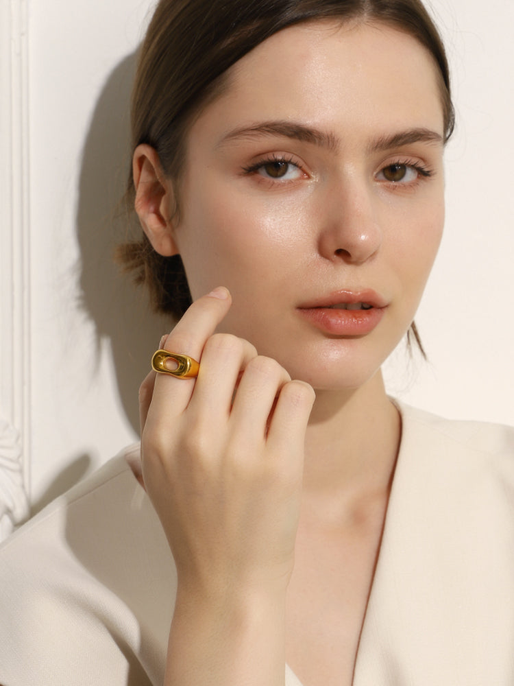 Woman wearing a gold ring on a neutral background