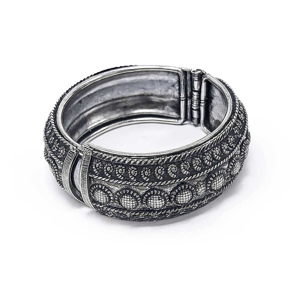 Silver bracelet with intricate design on a white background