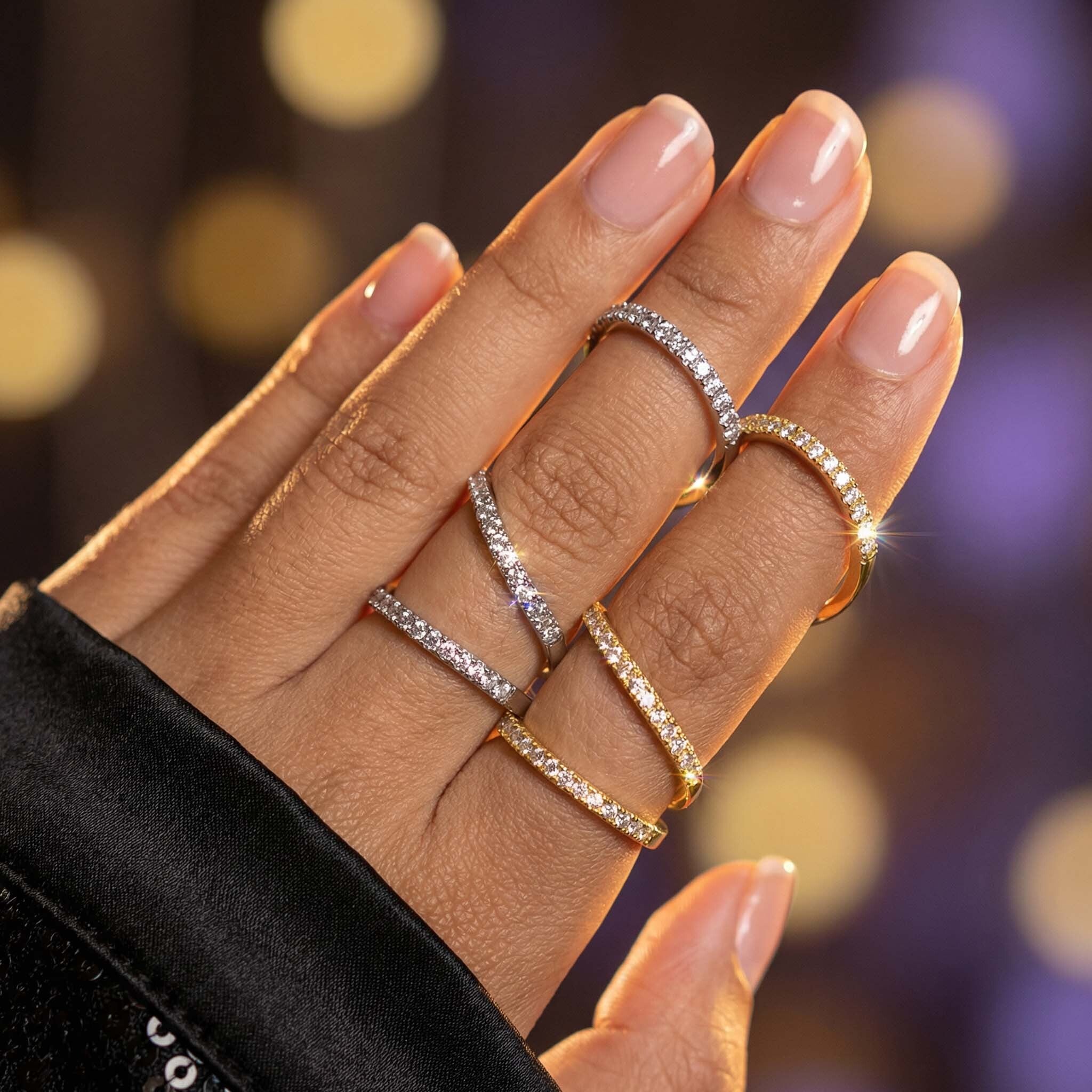 Hand wearing multiple diamond rings with a blurred bokeh background