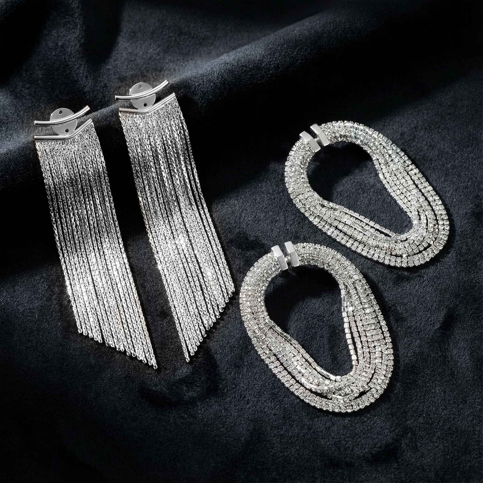Pair of silver fringe earrings and two silver hoop earrings on a dark fabric background