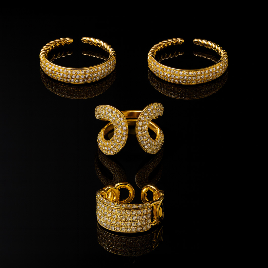 Set of gold jewelry including rings and a bracelet on a black background