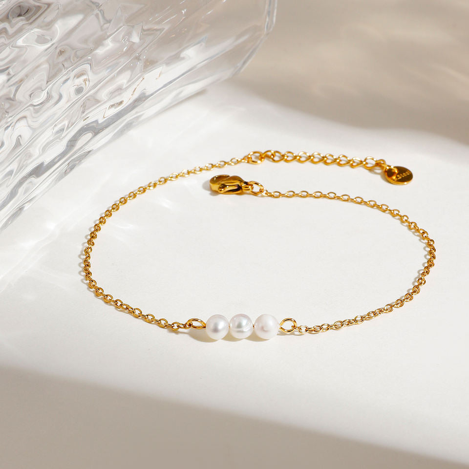 Gold anklet with pearls on a white surface