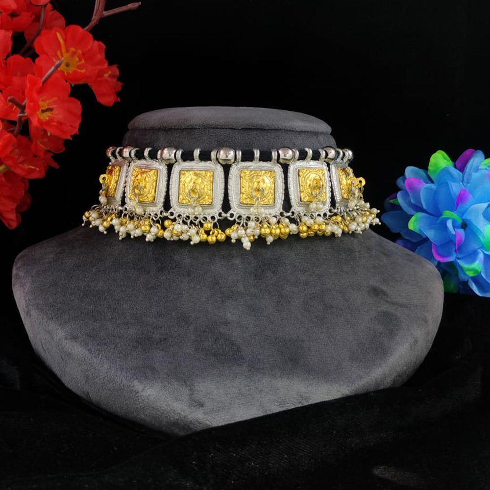 Decorative necklace with gold and silver elements on a gray stand against a black background with colorful flowers.
