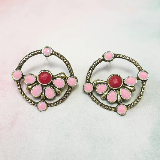 Pair of earrings with pink and red stones on a light background