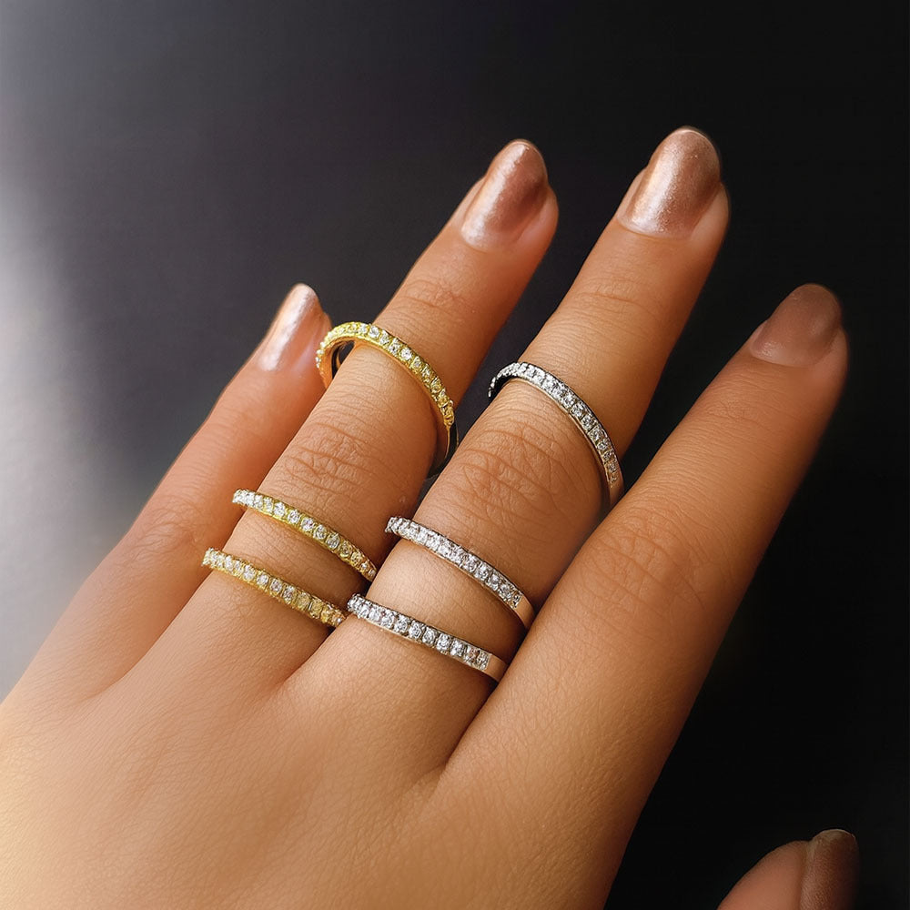 Hand wearing multiple diamond rings on a dark background