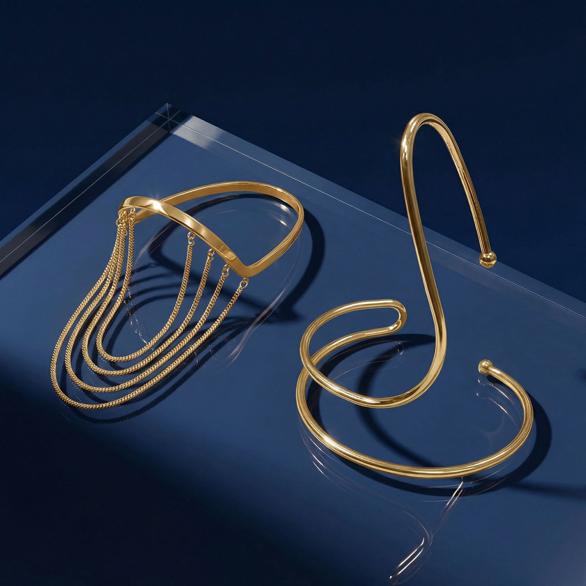 Gold bracelet and bangles on a reflective blue surface
