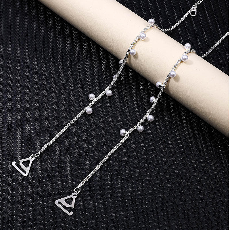 Silver chain bra strap with small beads on a black textured background