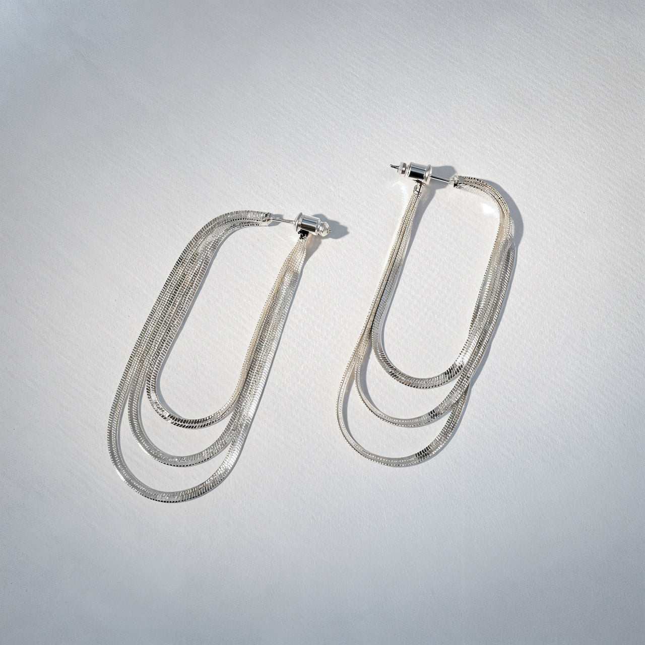 Pair of silver hoop earrings for women on a light gray background