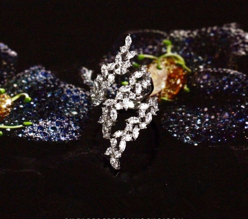 Silver leaf-shaped brooch with sparkling stones on a dark background