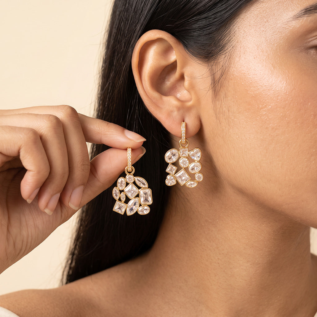 A close-up lifestyle shot of a model wearing a pair of gold and crystal cluster dangle earrings,