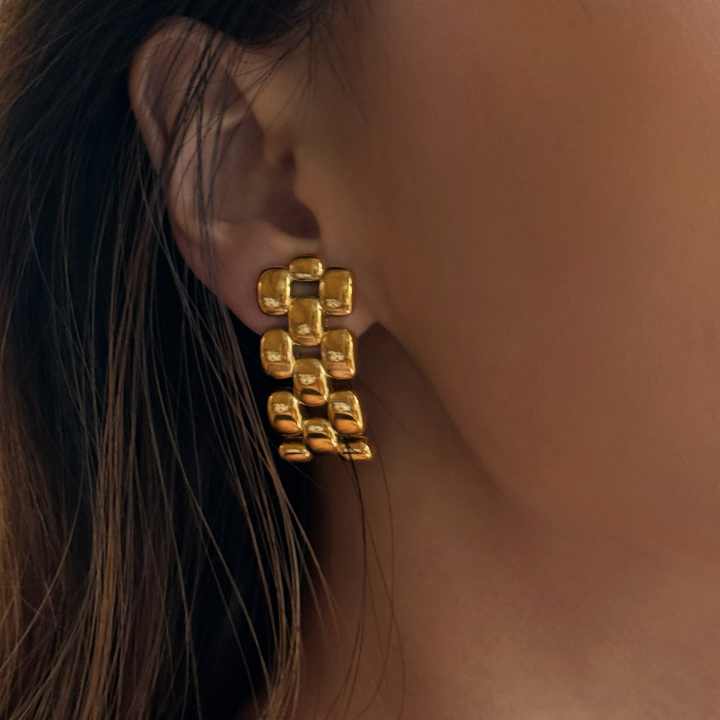 Gold geometric earrings for women worn by a person with dark hair.