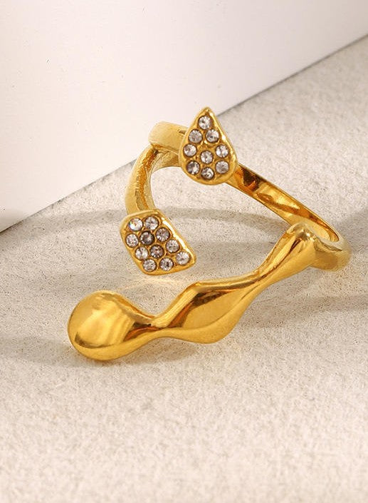 Gold ring with heart-shaped gemstones on a light background
