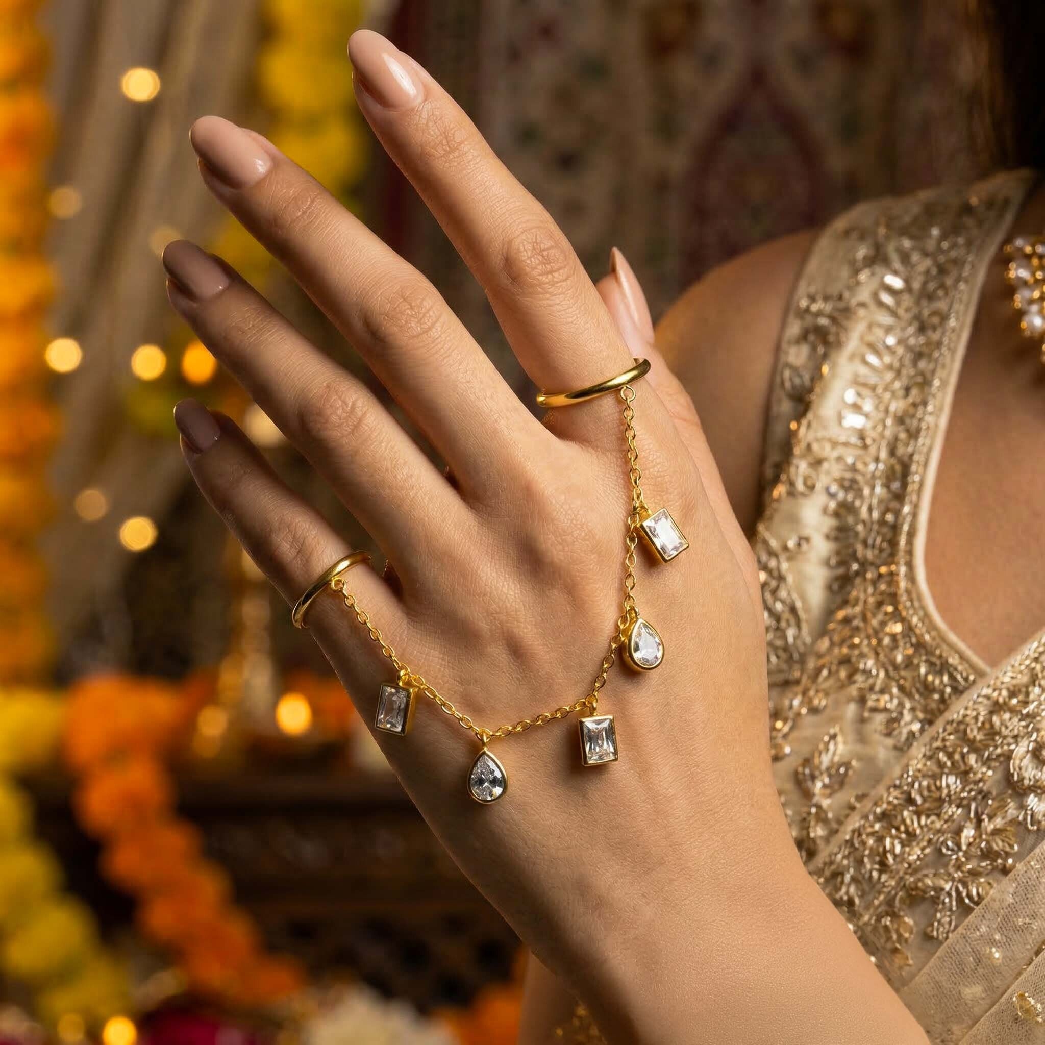 Hand wearing gold rings with diamond accents against a blurred decorative background