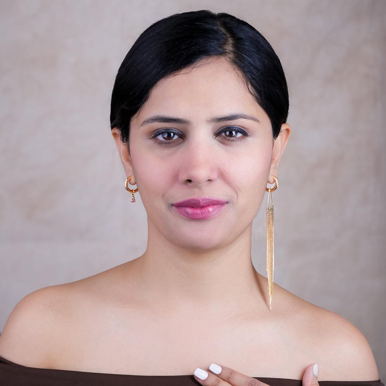 Woman wearing gold earrings against a neutral background