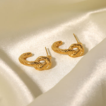 Gold hoop earrings on a satin surface