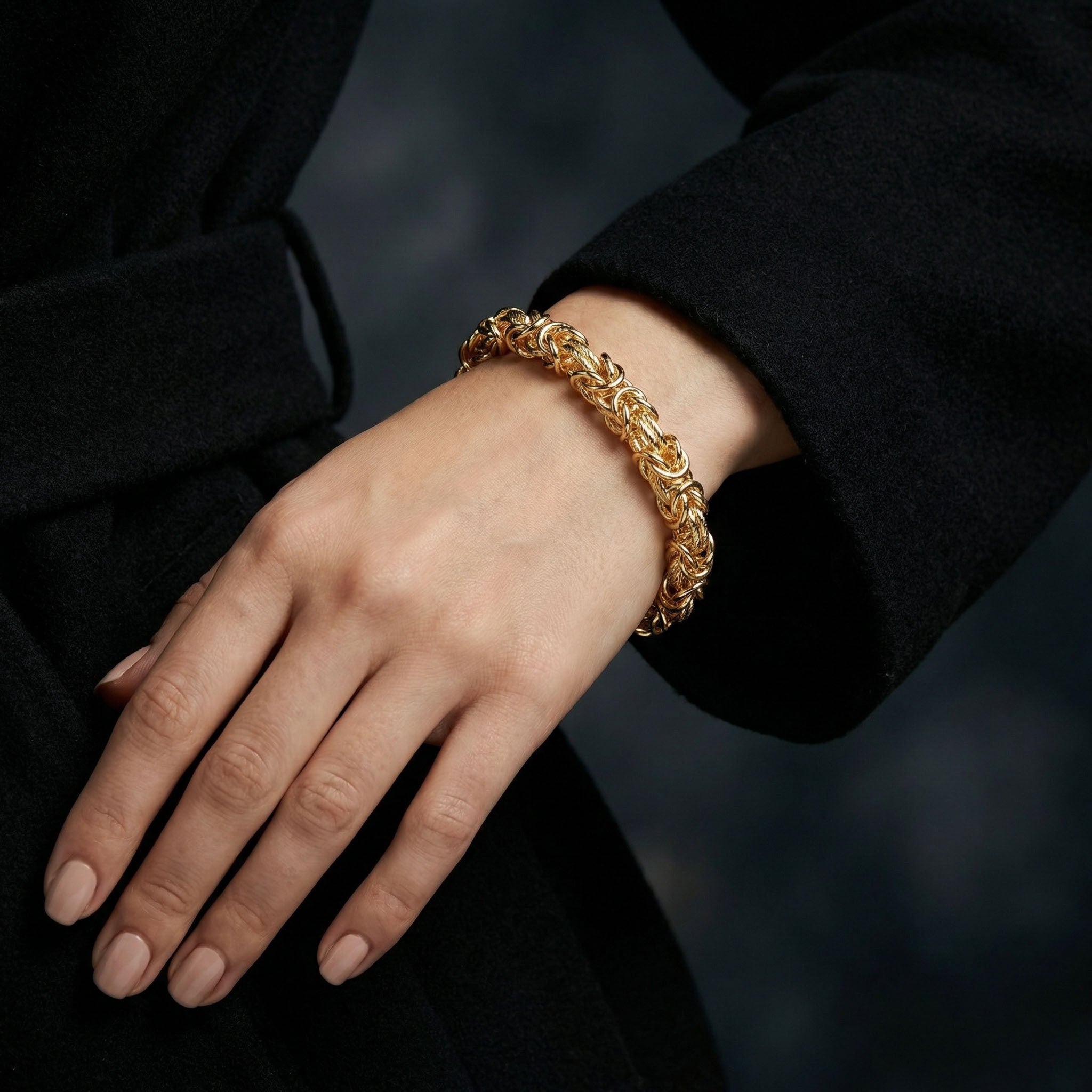 Gold chain bracelet on a person's wrist with a blurred background