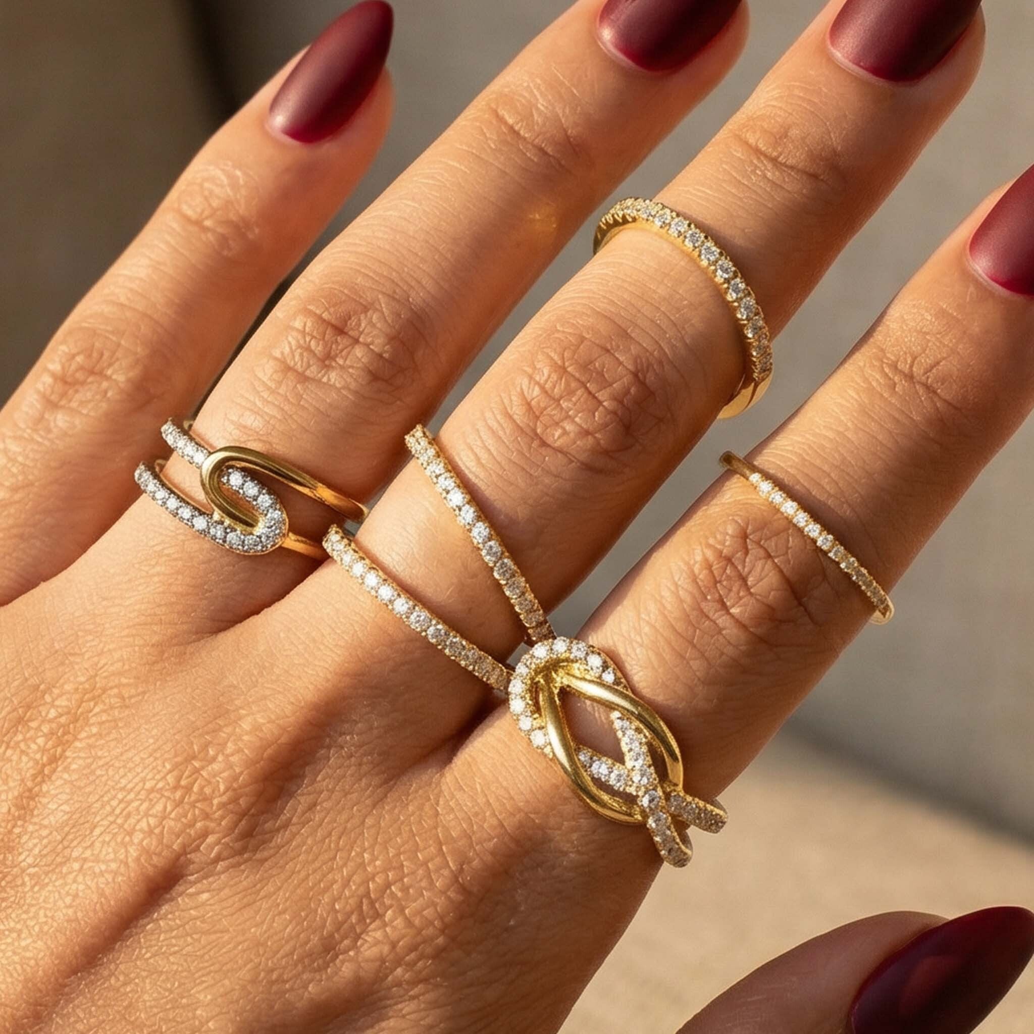 Hand wearing multiple gold and diamond rings with a blurred background