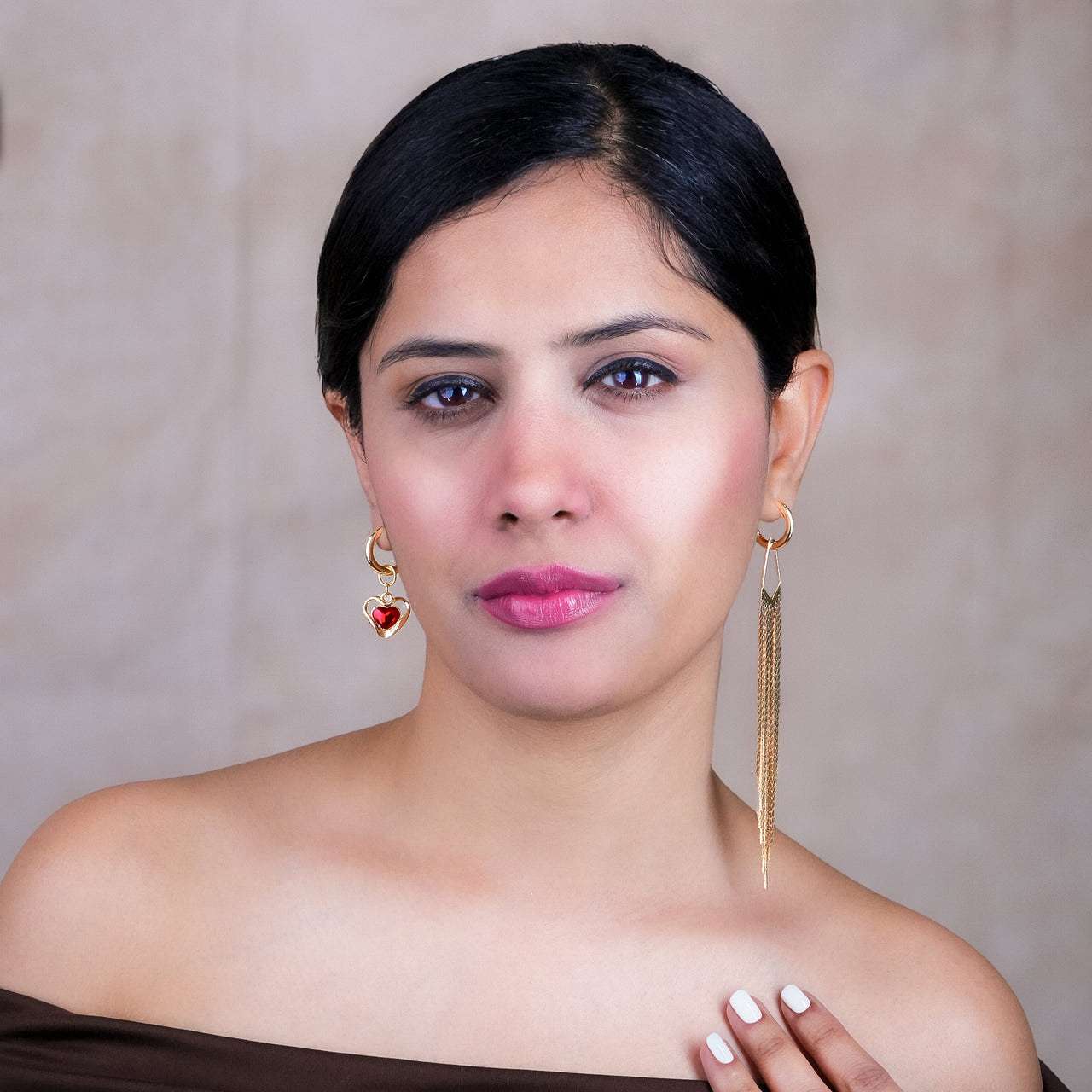 Woman wearing gold earrings with a plain background