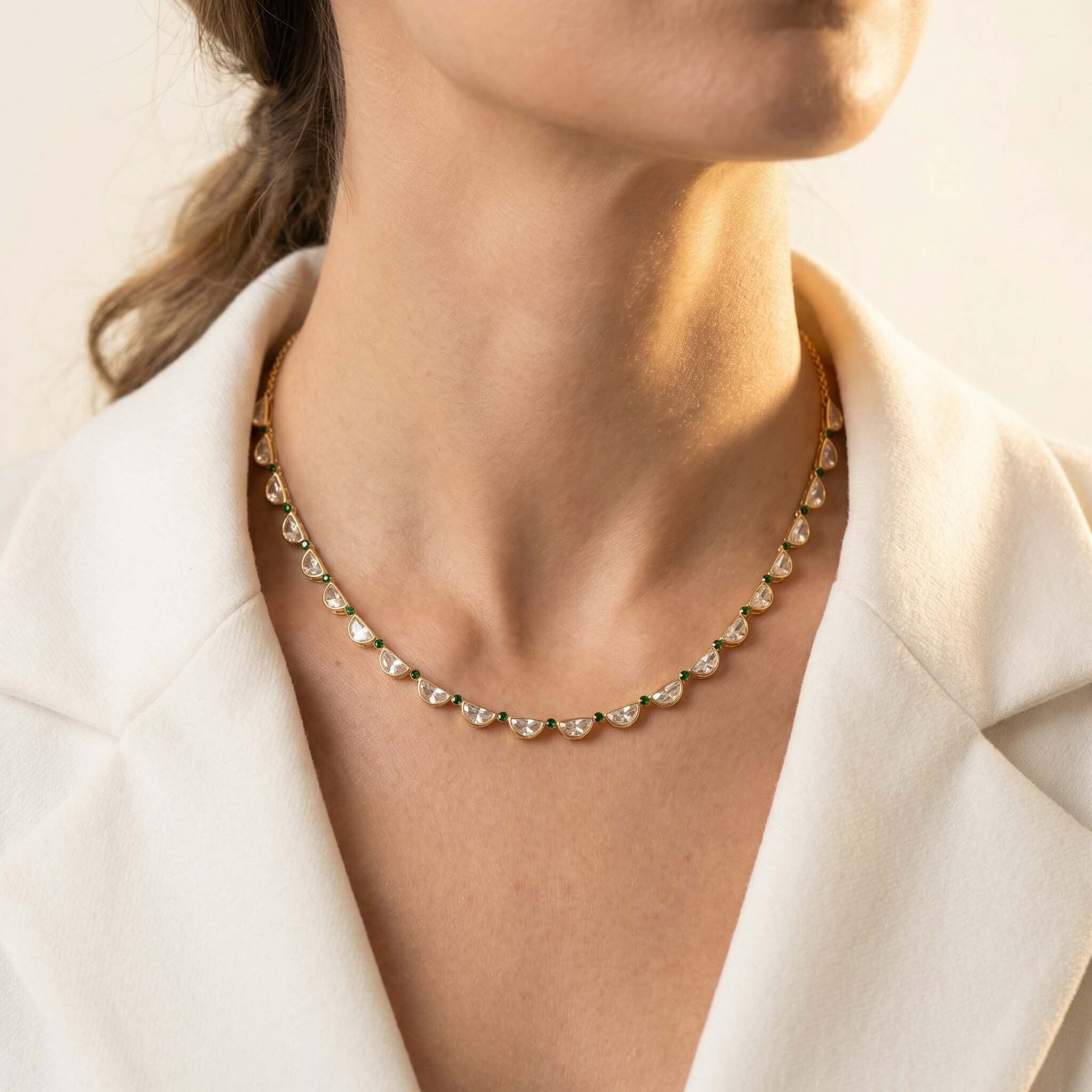 Gold necklace worn by a person with a neutral background
